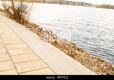 Fishing place with a fishing rod on the embankment of the river Stock Photo
