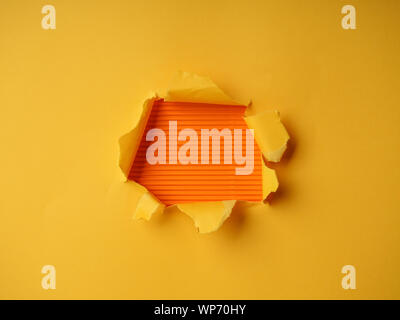 Wrinkled ripped torn red paper with hole in center background texture poster backdrop empty space. Stock Photo