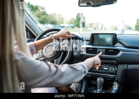 Close-up woman presses the emergency stop button, in the summer in the city, car interior, concept of a problem on the road, accident, notification of Stock Photo