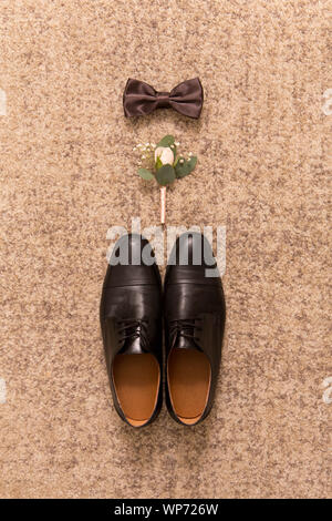 Black shoes, boutonniere and bow tie on floor background Stock Photo