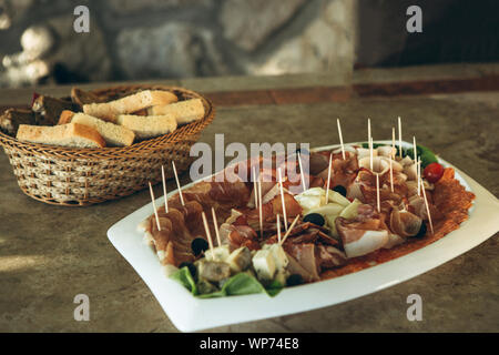 Plate with various meat snacks and cheese. In the background is a plate of bread. Stock Photo