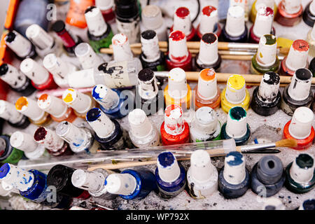 Dirty colorful paint bottles and brushes. Artist palette. Stock Photo