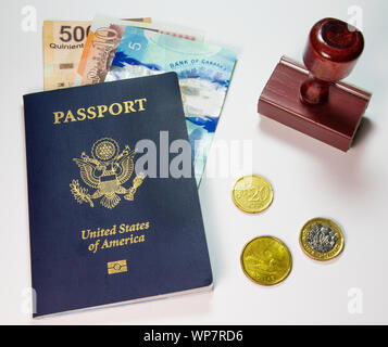Travel Concept with blue U.S. American Passport, Stamp and Foreign Currency displayed on a plain background Stock Photo