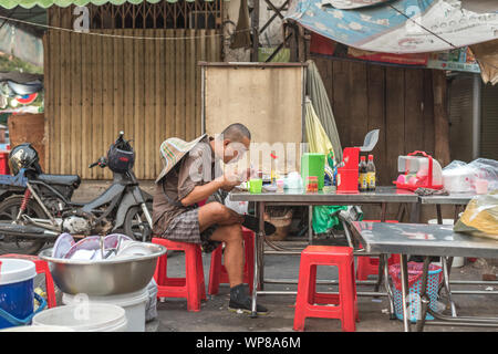 Phnom Penh, Cambodia - February 4, 2019: a lone Asian traveler eats at the table in a street restaurant. Stock Photo