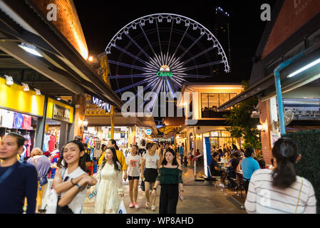 Bangkok, Thailand - July 28, 2019: a crowded alley at Asiatique The Riverfront at night, with a view of the Ferris wheel. Stock Photo