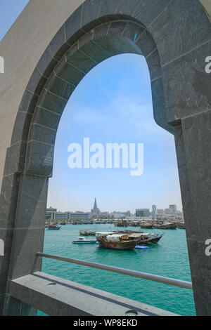 Outside architectural arch on Museum of Islamic Arts with view across Doha Boat harbor to city skyline.
