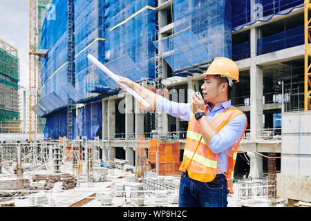 Young Vietnamese civil engineer managing process of work at construction site Stock Photo