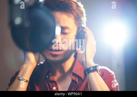 young asian musician singer singing song in recording studio Stock Photo