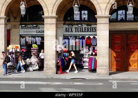 Souvenir shops and people walking under the arcade on rue de Rivoli across from the Tuileries Gardens, Paris, France. Stock Photo