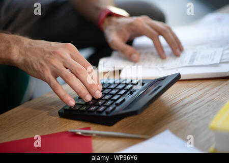 Close up of businessman using calculator lying near pen Stock Photo