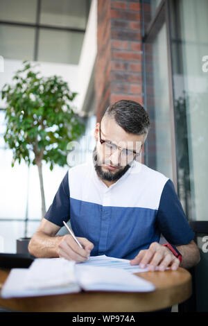 Bearded businessman making some notes while studying Stock Photo