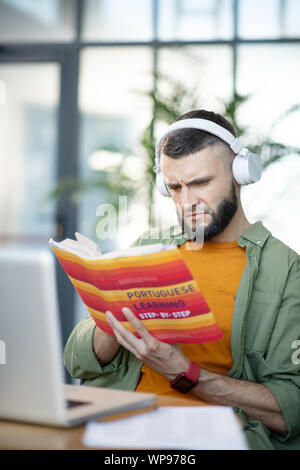 Bearded man listening and studying Portuguese language Stock Photo