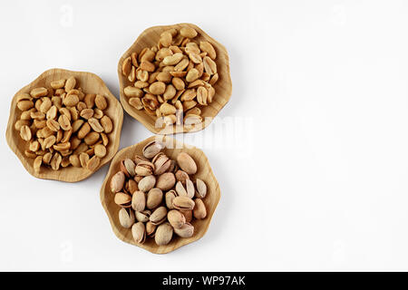 wood plates of salted peanuts and pistachios on white background. snack to beer Stock Photo