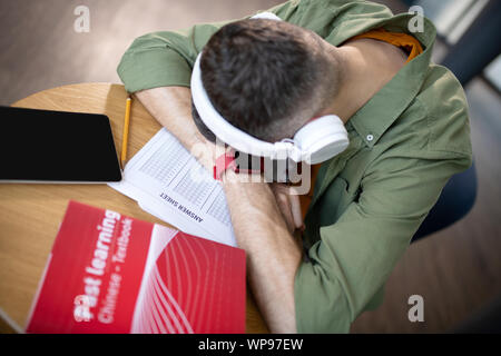 Student wearing earphones and smart watch feeling sleepy Stock Photo