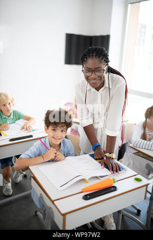 Teacher in glasses smiling broadly enjoying working with kids Stock Photo