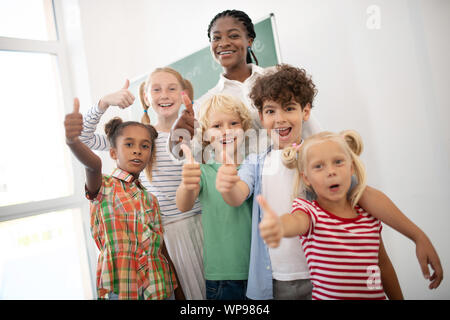 Children showing thumbs up while feeling amazing after lesson Stock Photo
