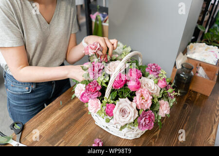 Woman florist create flower arrangement in a wicker basket. Beautiful bouquet of mixed flowers. Floral shop concept . Handsome fresh bouquet. Flowers Stock Photo