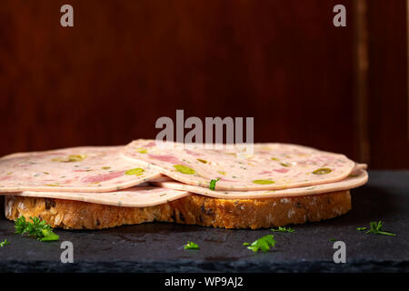 Open sandwich with Salami made from green vegetables like olives and pepper on a dark slate Stock Photo