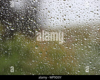 Closeup Raindrops on Window with Green Garden Background Stock Photo