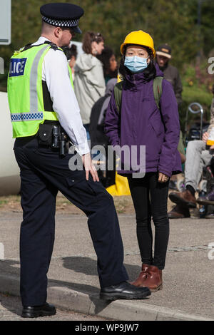 London, UK. 7 September, 2019. An activist wearing a mask and yellow helmet in solidarity with pro-democracy campaigners in Hong Kong speaks to a Metr Stock Photo