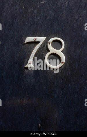House number 78 from victorian times on a black wooden front door Stock Photo