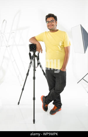 Photographer leaning on a digital camera in studio Stock Photo