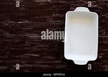 Ceramic white baking dish on a wooden old background. Selective focus. Stock Photo