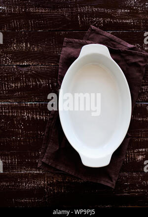 Ceramic white baking dish on a wooden old background. Selective focus. Stock Photo