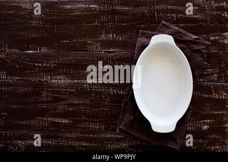 Ceramic white baking dish on a wooden old background. Selective focus. Stock Photo