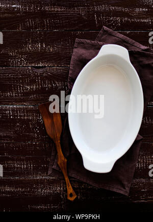 Ceramic white baking dish on a wooden old background. Selective focus. Stock Photo