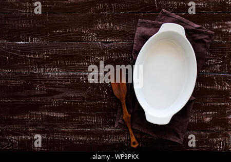 Ceramic white baking dish on a wooden old background. Selective focus. Stock Photo