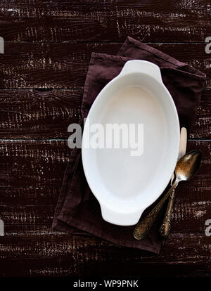 Ceramic white baking dish on a wooden old background. Selective focus. Stock Photo