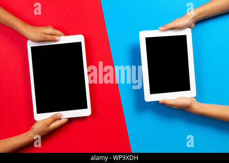 Kids holding tablet computer over red and light blue background Stock Photo