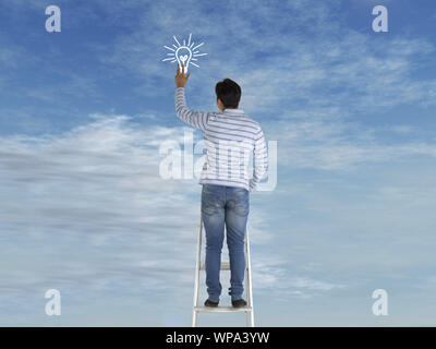 Man standing on ladder of success and holding light bulb Stock Photo