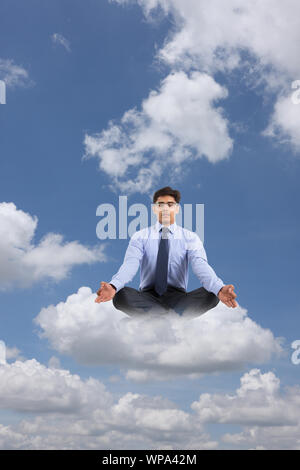 Businessman sitting on clouds practicing yoga Stock Photo