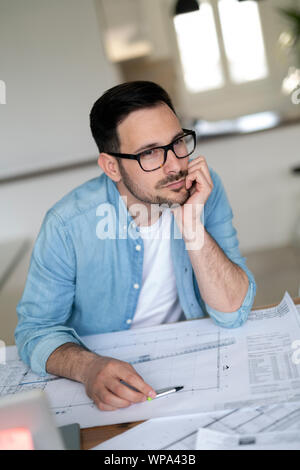 Thoughtful young architect man holding hand on chin and looking away Stock Photo