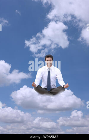 Businessman sitting on clouds practicing yoga Stock Photo