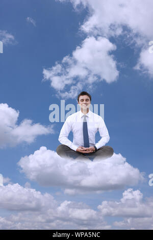 Businessman sitting on clouds practicing yoga Stock Photo