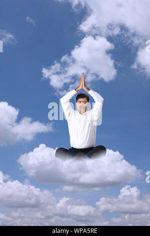 Businessman sitting on clouds practicing yoga Stock Photo
