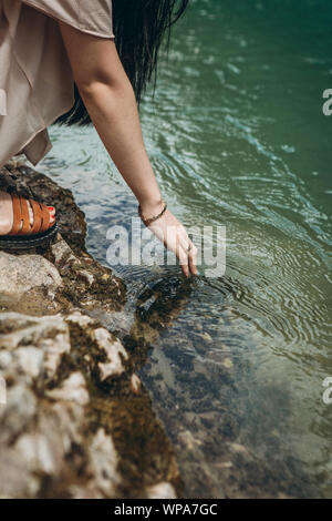 Close-up of a girl touching water in a river or pond or lake. Unity with nature. Stock Photo