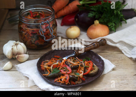 Vegetable salad of eggplant, sweet pepper, carrots and onions and vegetables for salad on a wooden background. Stock Photo