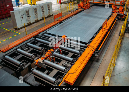 Steel sheet moving on roller conveyor in metalworking workshop. Stock Photo