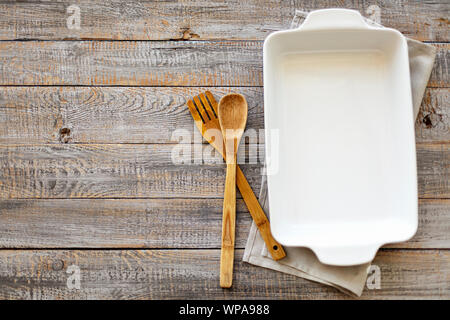 Ceramic white baking dish on a wooden old background. Selective focus. Stock Photo