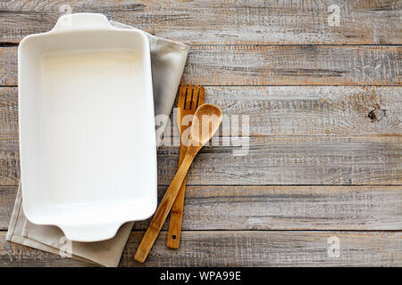 Ceramic white baking dish on a wooden old background. Selective focus. Stock Photo