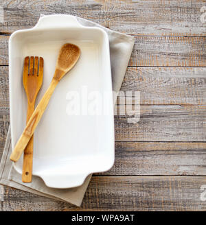 Ceramic white baking dish on a wooden old background. Selective focus. Stock Photo