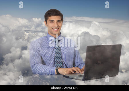 Businessman sitting on clouds working on a laptop Stock Photo