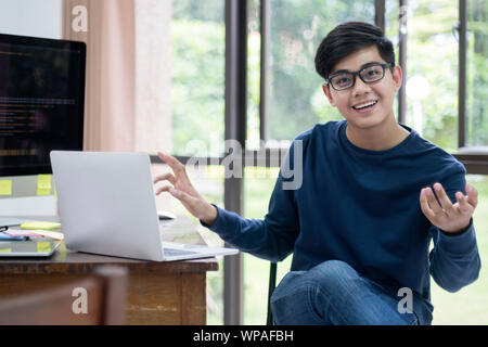 Handsome casual  businessman is looking at camera and smiling while presenting the work in office. Stock Photo