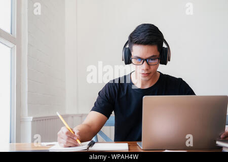 Young  man student study at home. He using laptop and learning online. Stock Photo