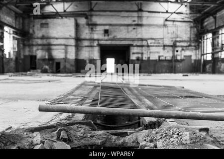 Low angle and close up view at falling metal fence lay on damage floor of interior empty open floor of abandon former workshop factory with nobody. Stock Photo