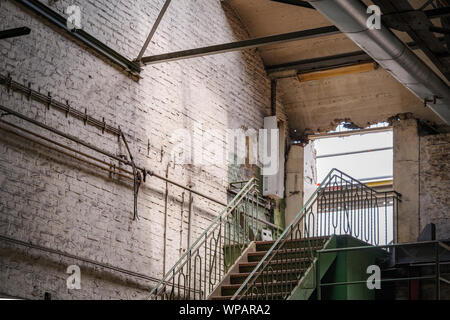 Interior view of the hole of demolishing wall at the top of steel staircase inside old brick building of former abandon factory or industrial building Stock Photo